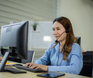 Young woman with long brown hair on a computer with a headset