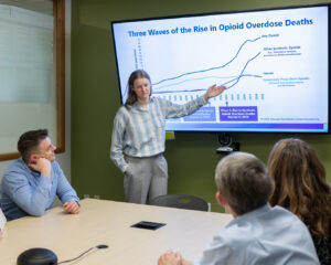 woman giving a presentation demonstrating a slide with a graph.
