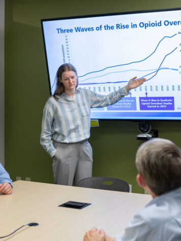 woman giving a presentation demonstrating a slide with a graph.