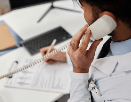 close-up photo of a doctor's hands talking on the phone while writing