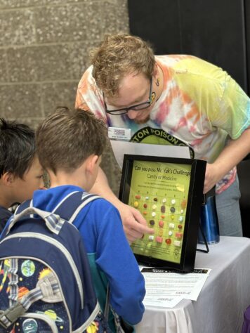 Man showing two kids a display that shows the similarities between candies and medicines