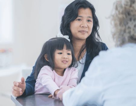 Woman with small child talking to a woman in a white coat with her back to the camera